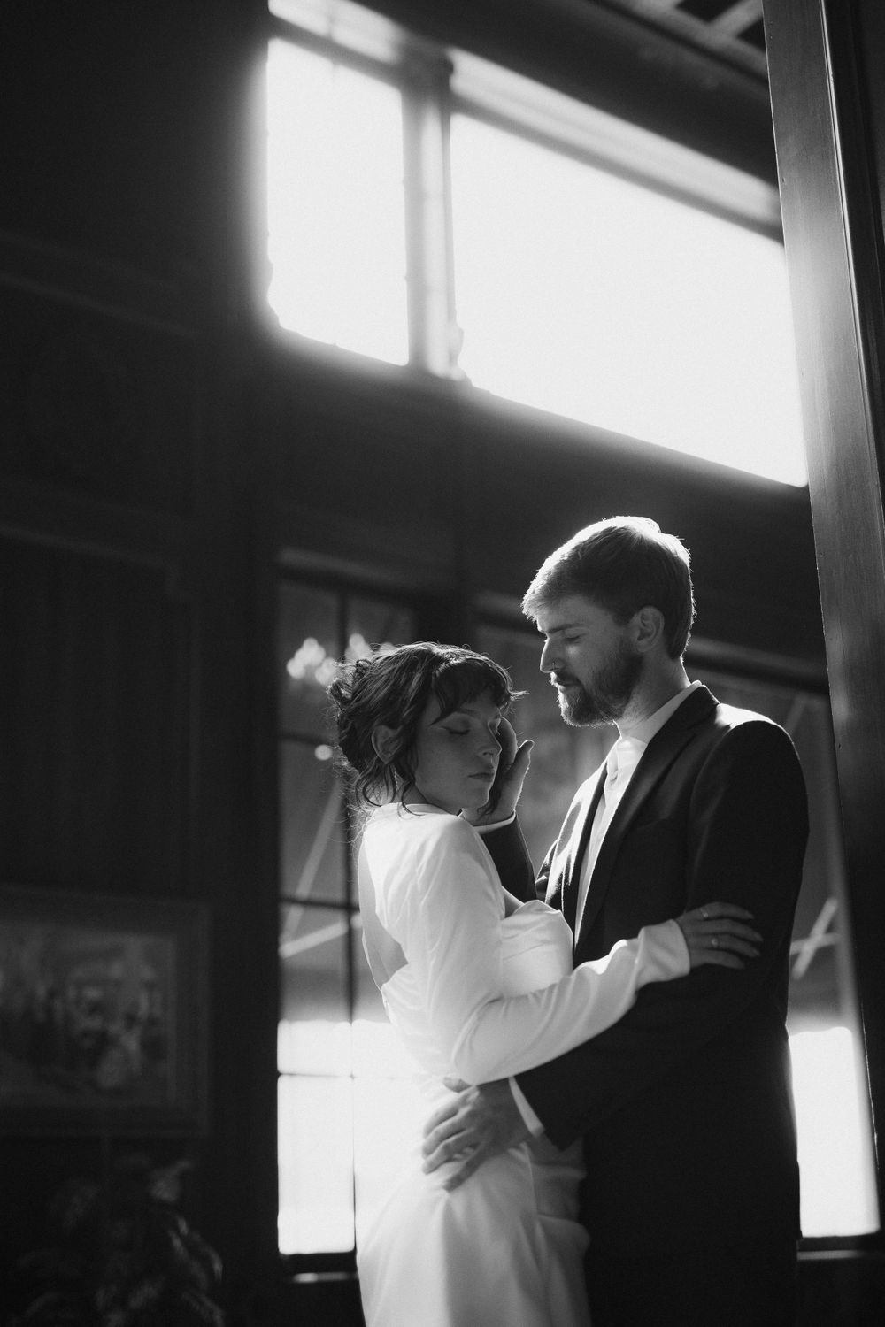 Artistic black and white photos of a romantic dance moment backlit by window light.