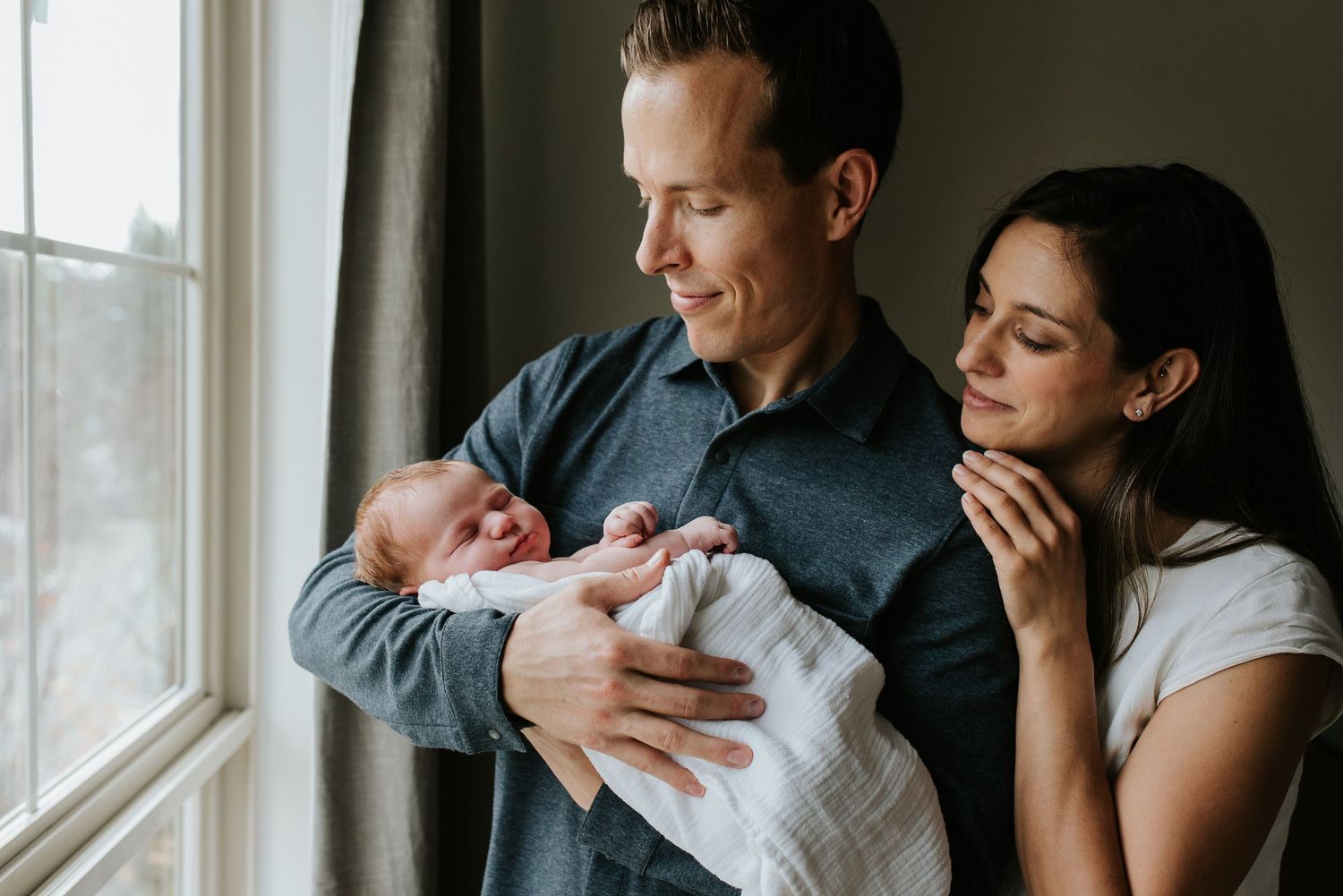 Dad holding newborn baby girl with Mom snuggling in beside him