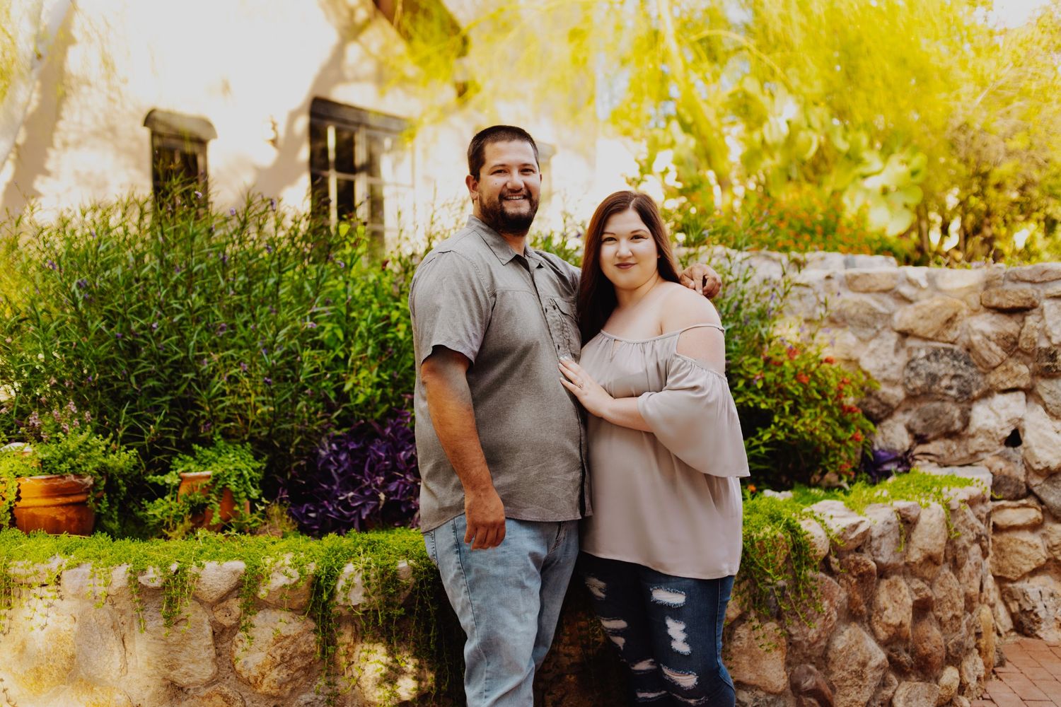 A casual couple's portrait session against a stone wall backdrop with autumn trees.