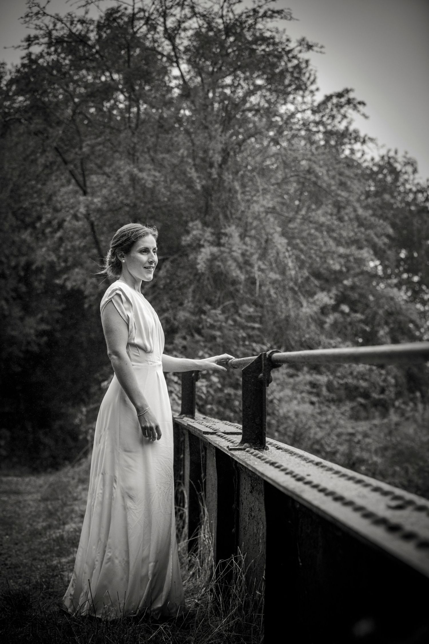 Black and white portraits of a person in a wedding dress leaning on a wooden railing.