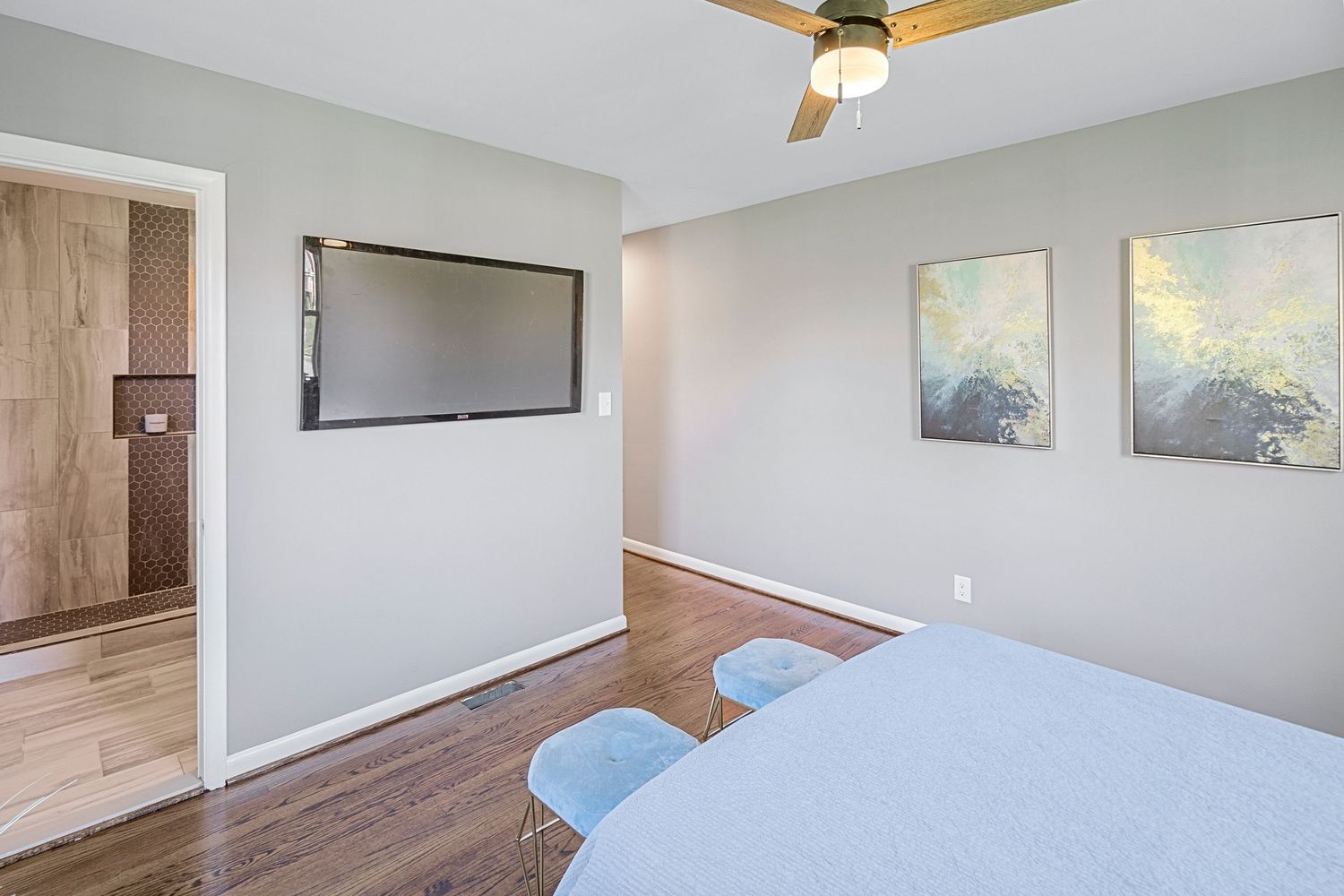 Bedroom featuring wall-mounted TV, abstract art, and modern furnishings.