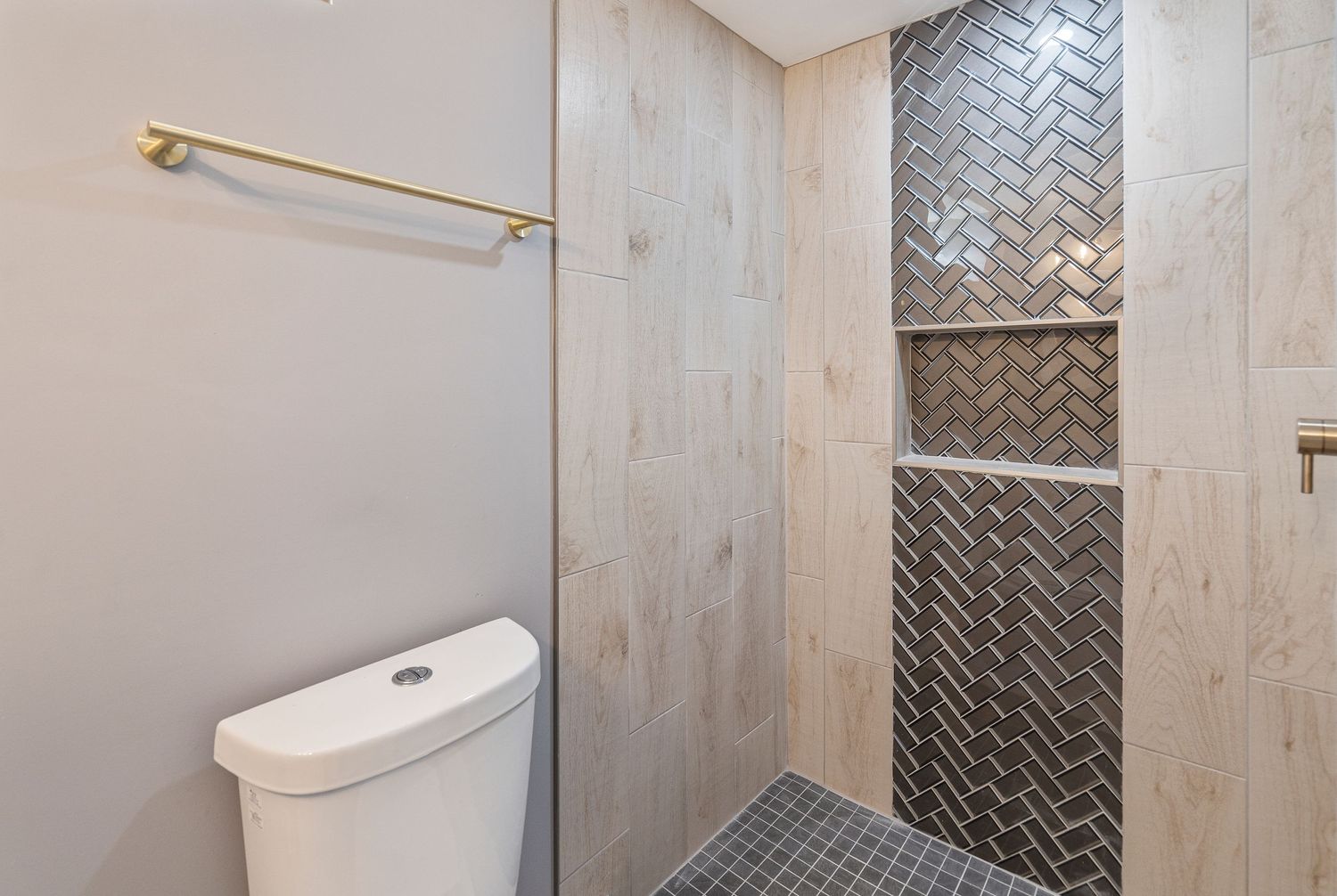 Modern bathroom with herringbone tile pattern and glass shower enclosure.