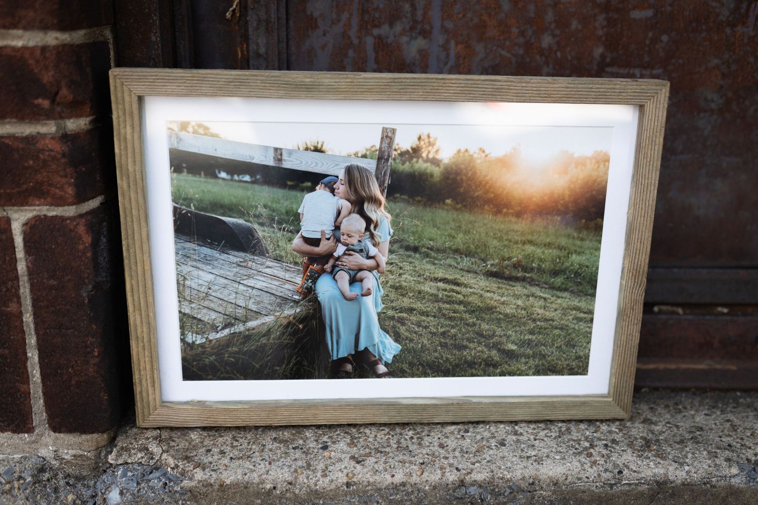Framed family photograph displayed against rustic brick wall at sunset.