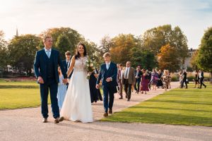 Wedding party walks along a scenic path during an autumn celebration.