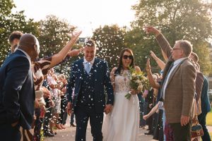 Wedding guests shower the newlyweds with confetti during an outdoor celebration.