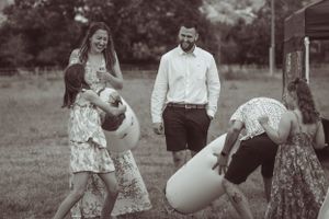 Wedding party plays lawn games and celebrates outdoors in summer attire.