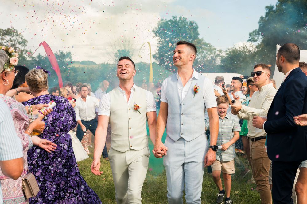 Outdoor wedding celebration with colored smoke and confetti creating a joyful atmosphere.