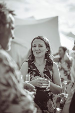 Black and white candid shot of guests enjoying conversation at wedding reception.