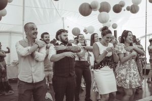 Wedding guests hold paper lanterns in a festive indoor celebration.