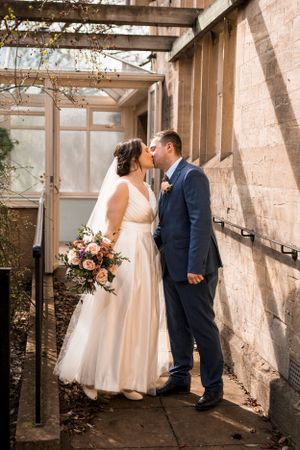 A wedding couple shares intimate moments in a rustic greenhouse setting.