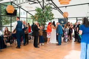 Wedding reception guests mingling and socializing in a decorated venue with hanging lanterns.