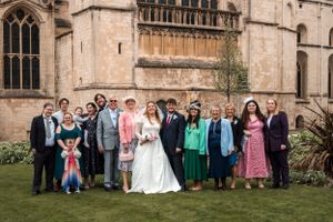 Wedding party group photo outside historic stone church building.