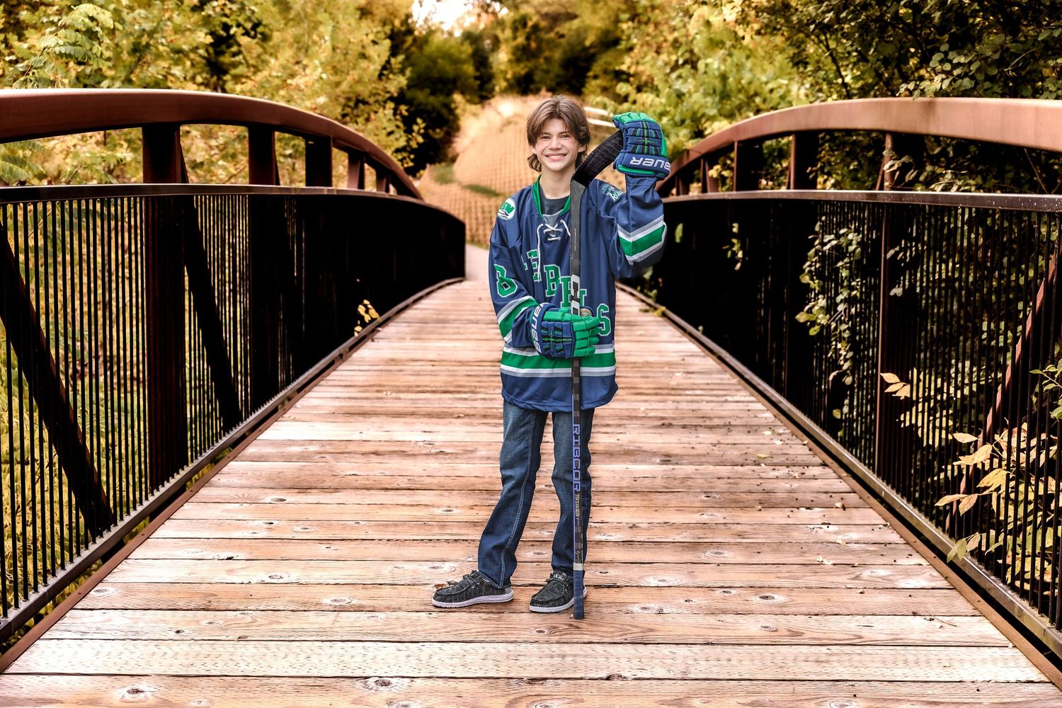 Person in sports gear standing on wooden bridge with backpack in fall setting.