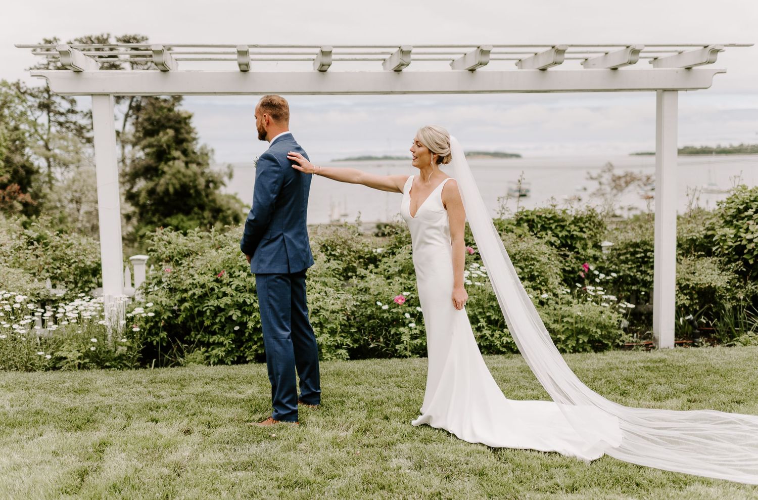 A romantic first look sequence under a white pergola on a sunny day.