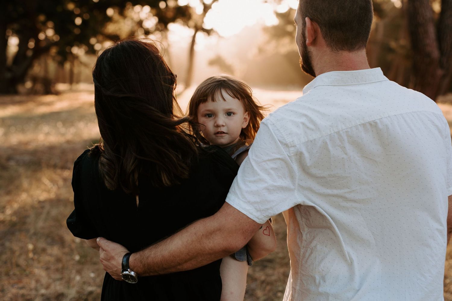 A family shares an intimate moment together outdoors during golden hour.