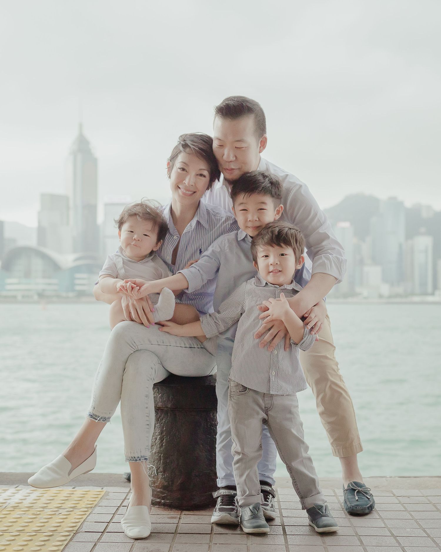 Family portrait of group hugging together against city skyline backdrop at waterfront.