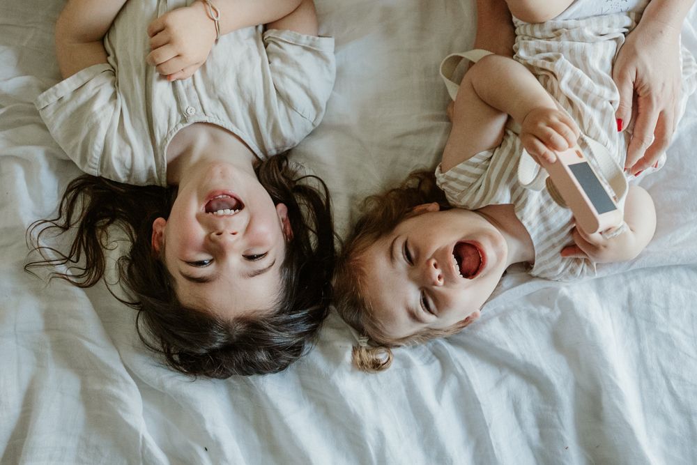 portrait de deux soeurs qui s"amusent avec les parents pendant une séance photo grossesse en famille à domicile à Lille