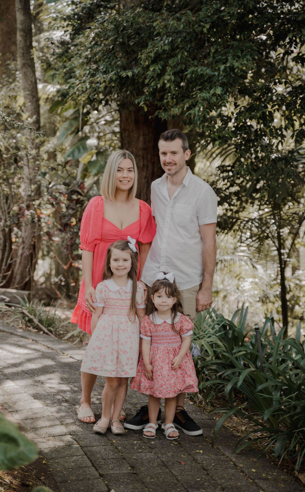 Family portrait on garden path with coral and pink coordinated outfits.