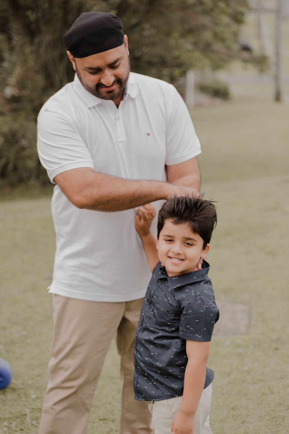 Playful moment shared between parent and child outdoors on a grassy area.