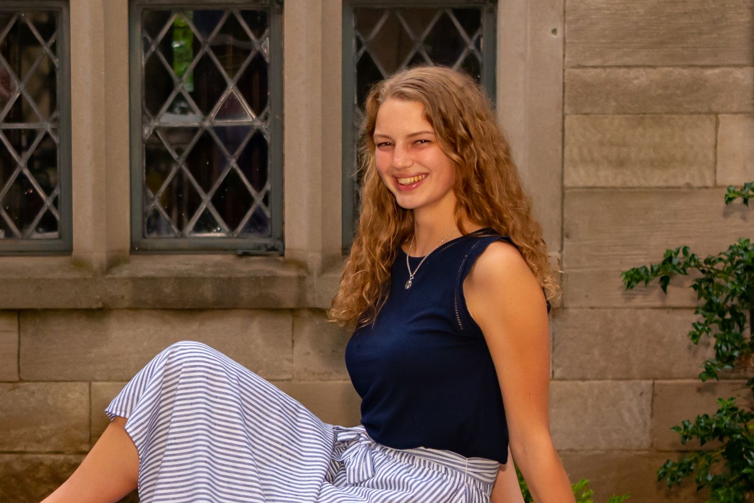 high school senior sitting in front of diamond shaped mansion window