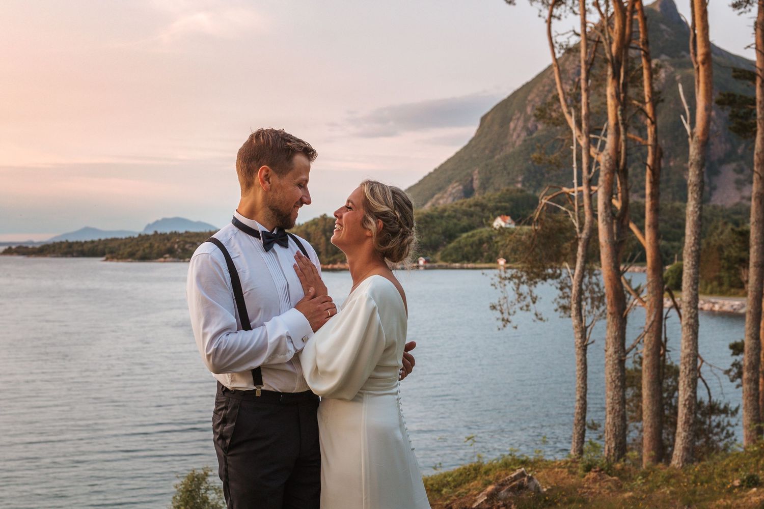 A romantic sunset wedding portrait with mountains and water in the background.