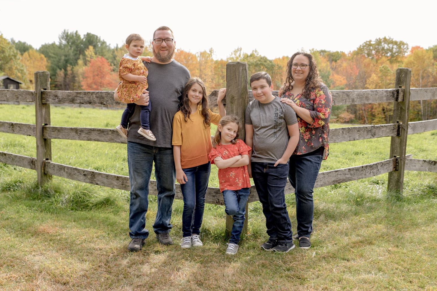 Family standing against fence, family photography
