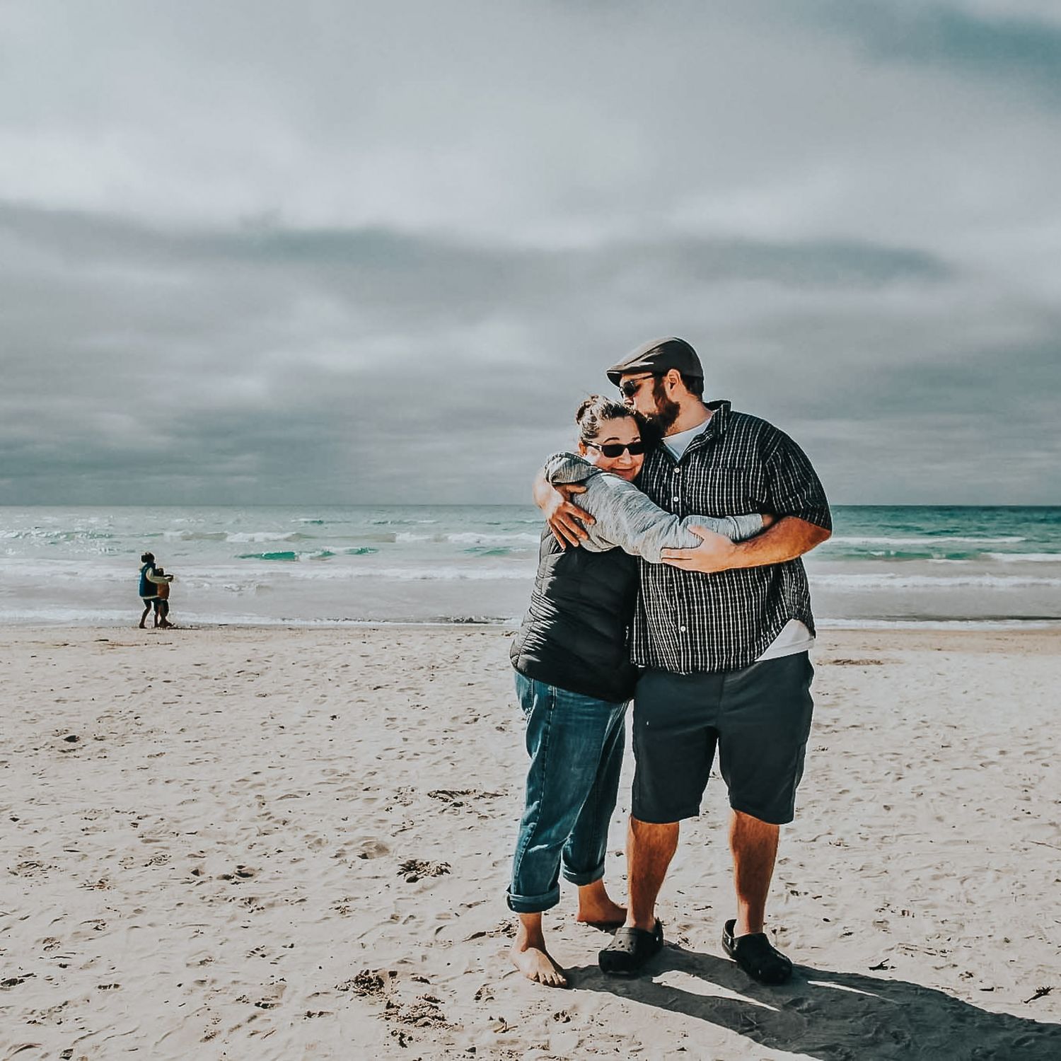 Mom and dad hold each other and dad kisses mom's head at Sauble Beach in September.