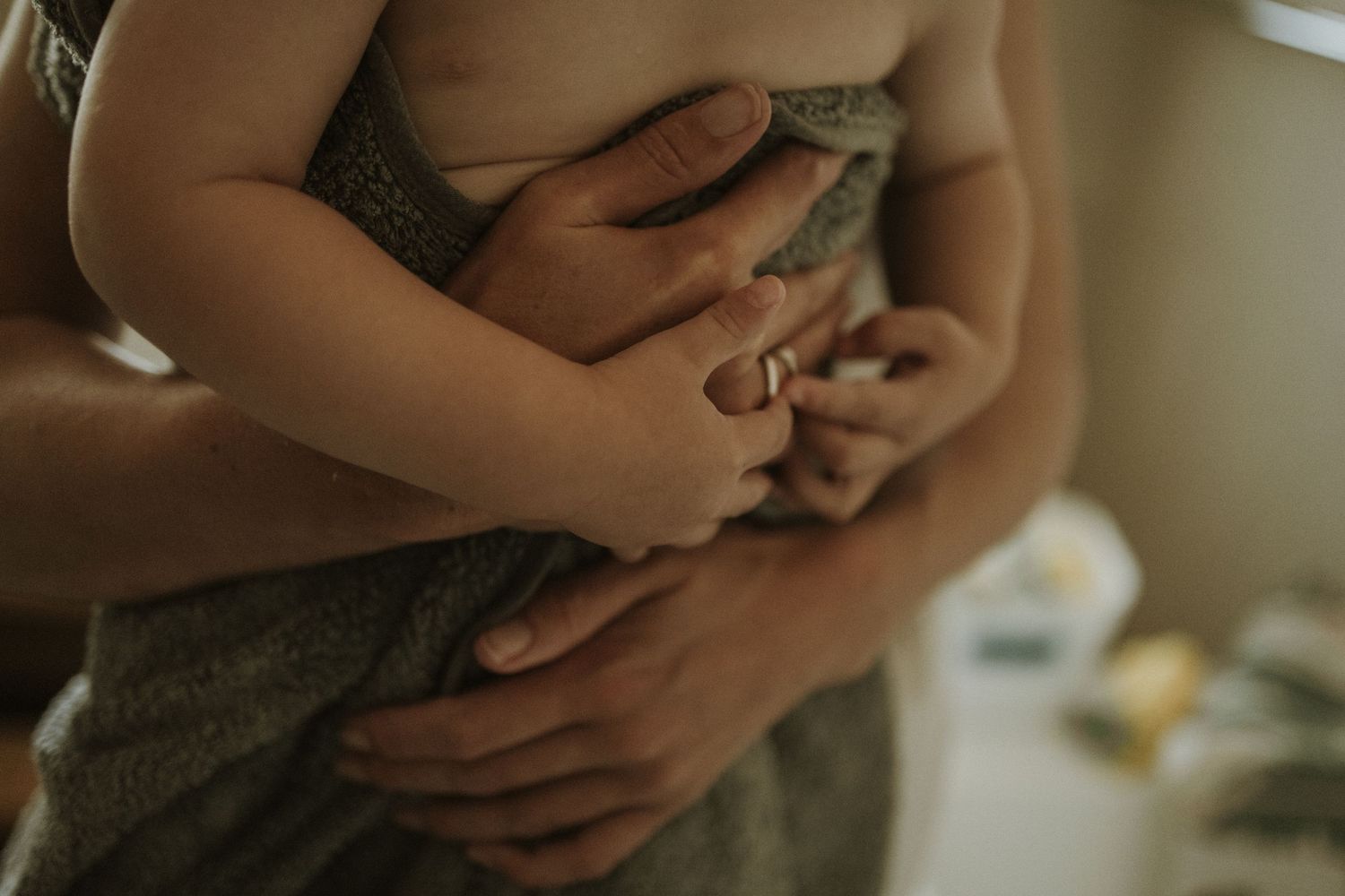 Intimate close-up of gentle hands holding and embracing in warm lighting.