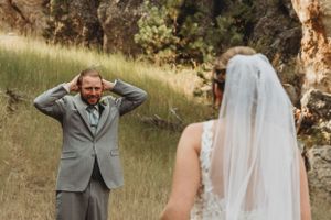 A first look wedding moment captured on a hillside with dramatic emotional reaction.