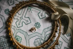 Wedding rings and a decorative gold crown rest on a patterned textile featuring geometric designs in green and white.