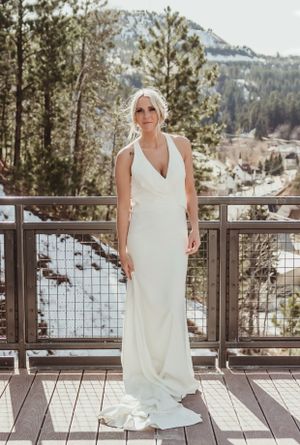 Classic white wedding dress displayed on deck with snow-capped mountain views.