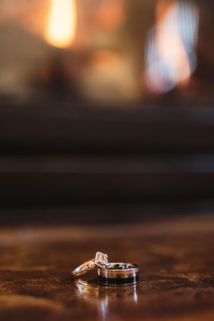 Wedding rings photographed with shallow depth of field on a wooden surface with warm lighting.