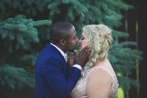 An intimate wedding moment captured against evergreen trees in the background.