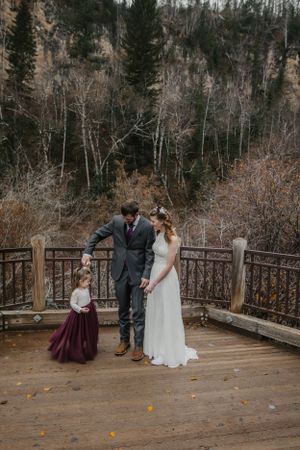 Wedding party on a rustic wooden deck overlooking a scenic forest landscape on an autumn day.