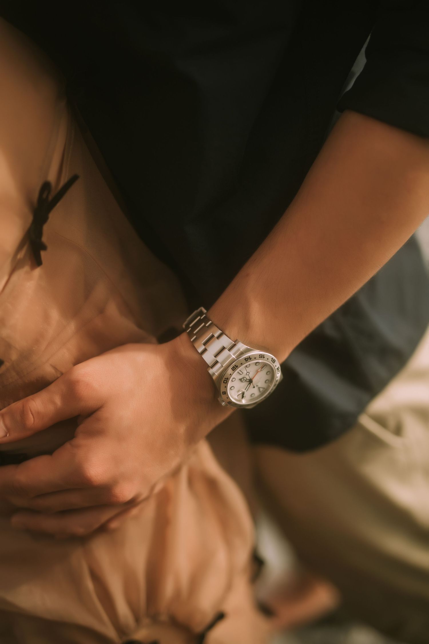 Detailed shot of hands and wristwatches in warm, intimate lighting.