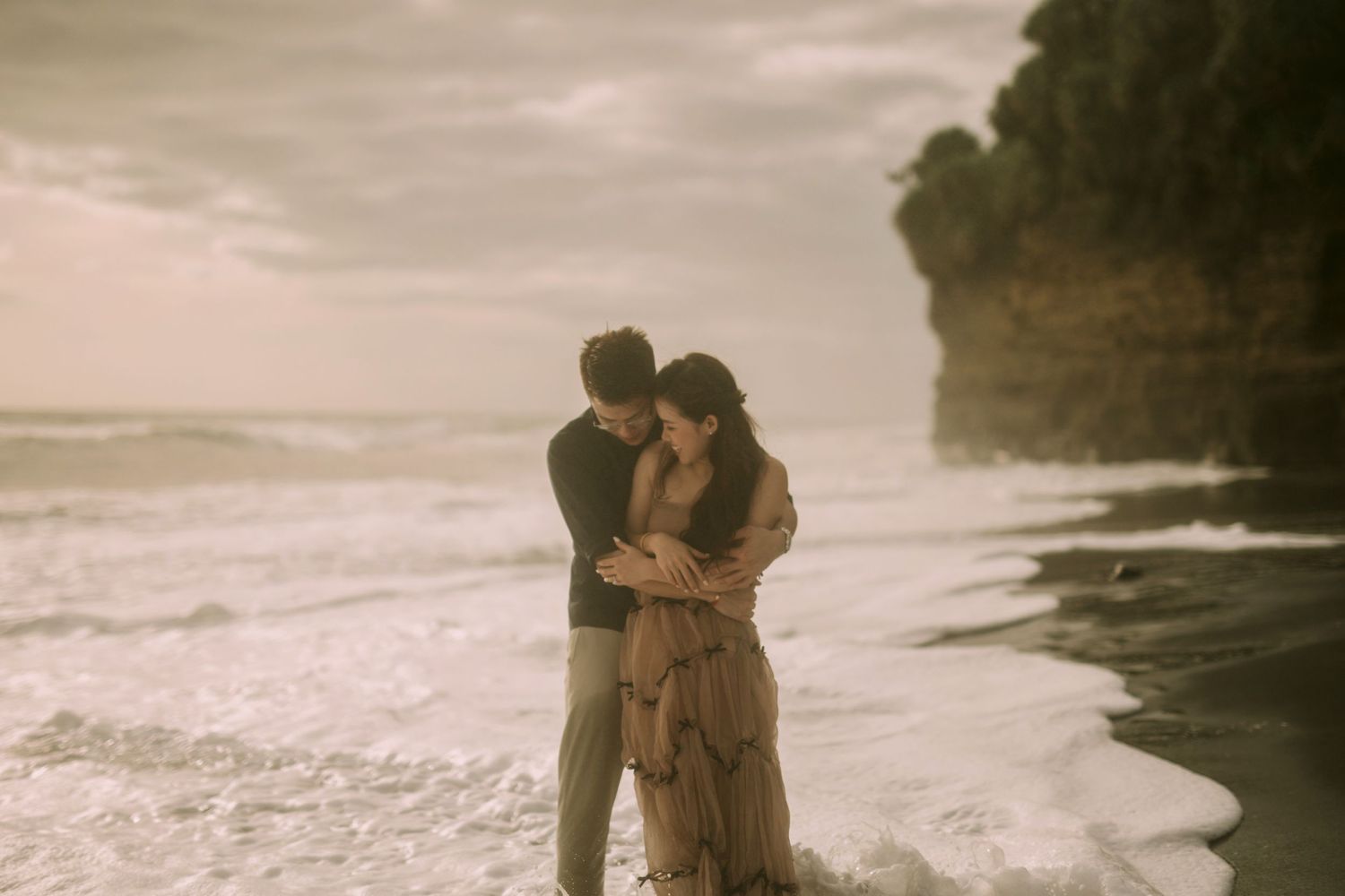 Romantic seaside photoshoot with dramatic coastal cliffs in sepia.