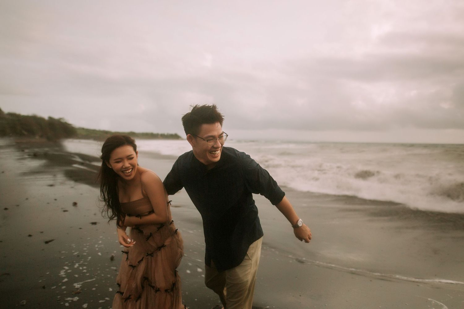 Two people share playful moments together along the ocean's edge.