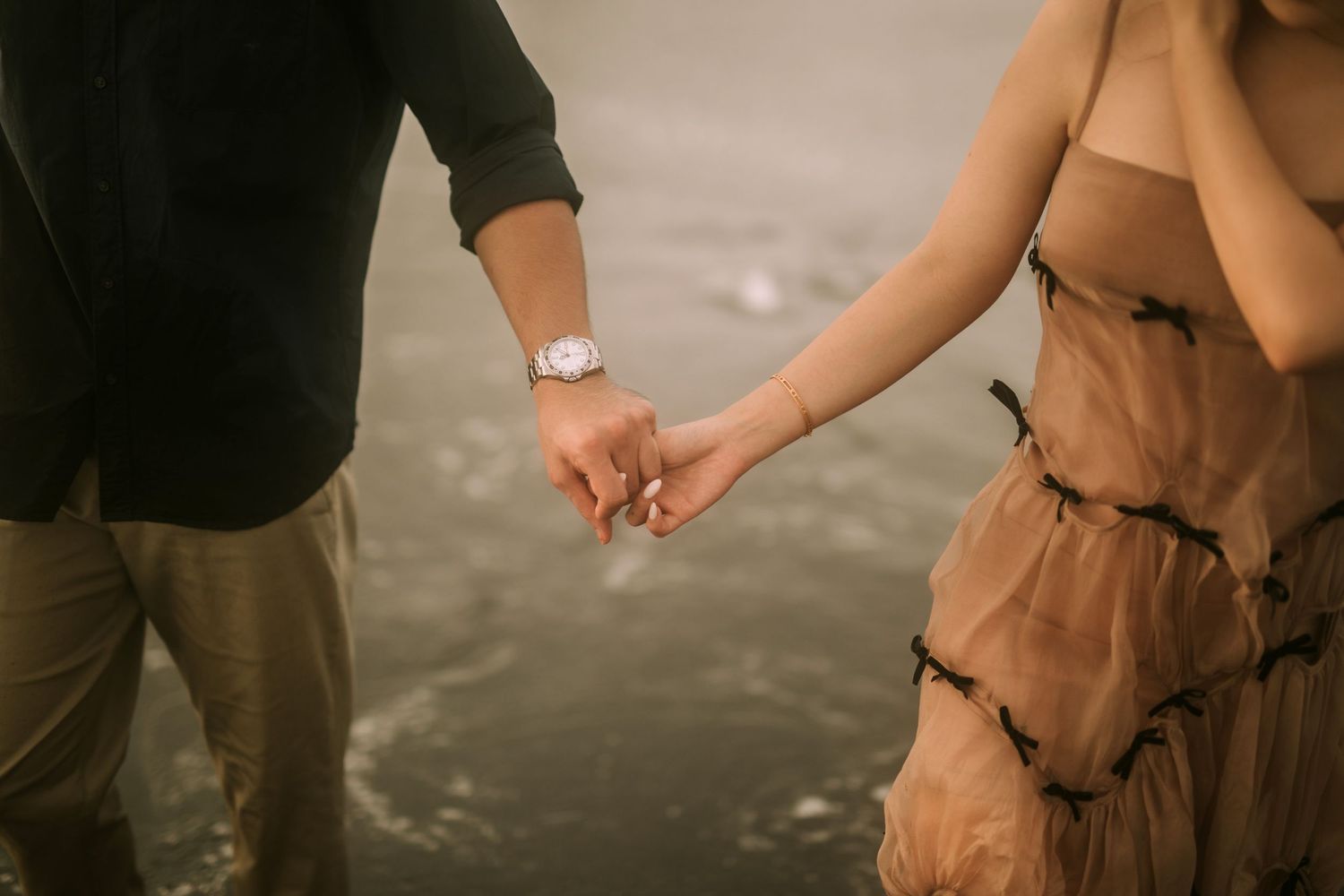 Close-up shot of two people's lower bodies on a sandy beach.