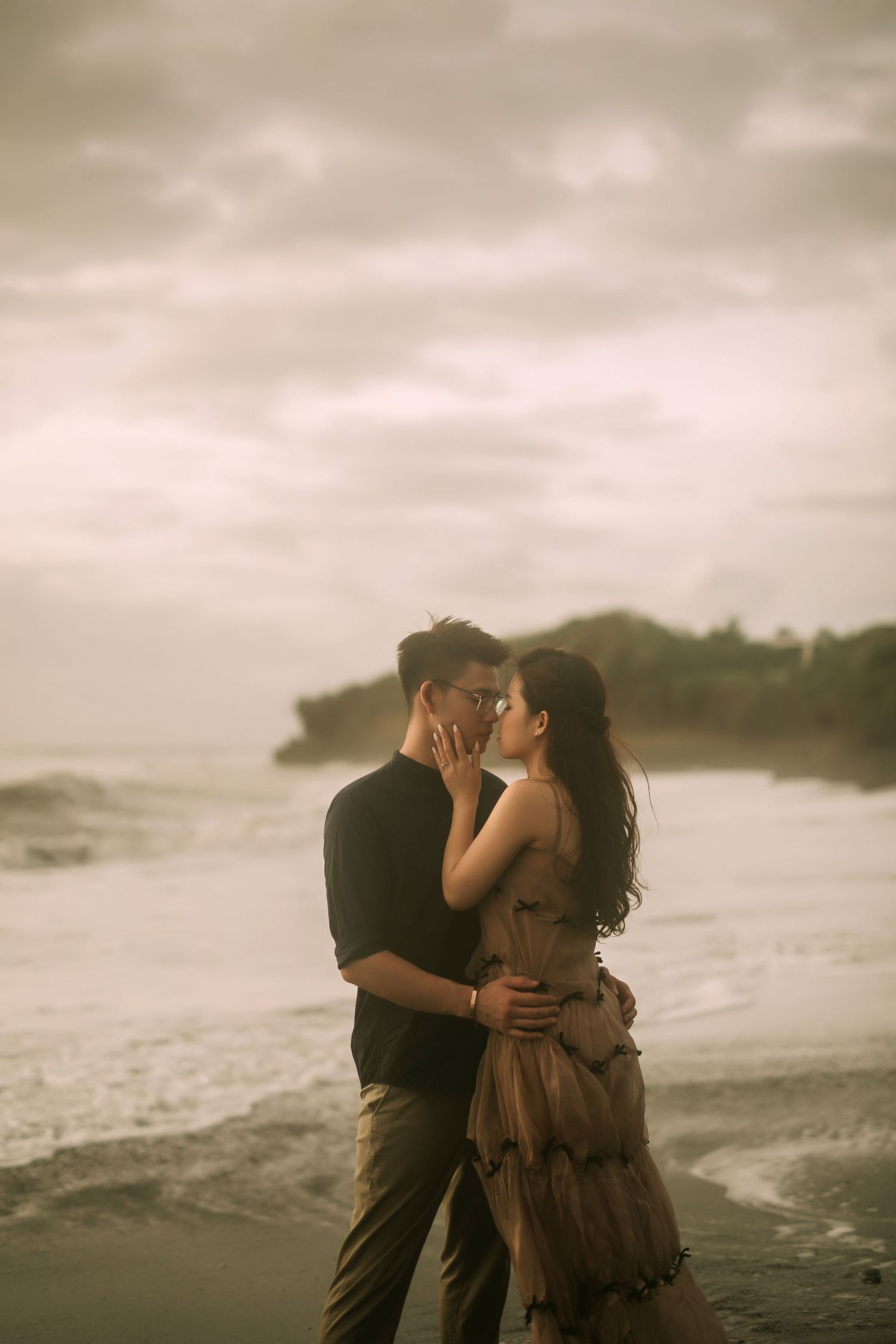 Silhouetted couple shares tender moments against a dramatic beach backdrop.