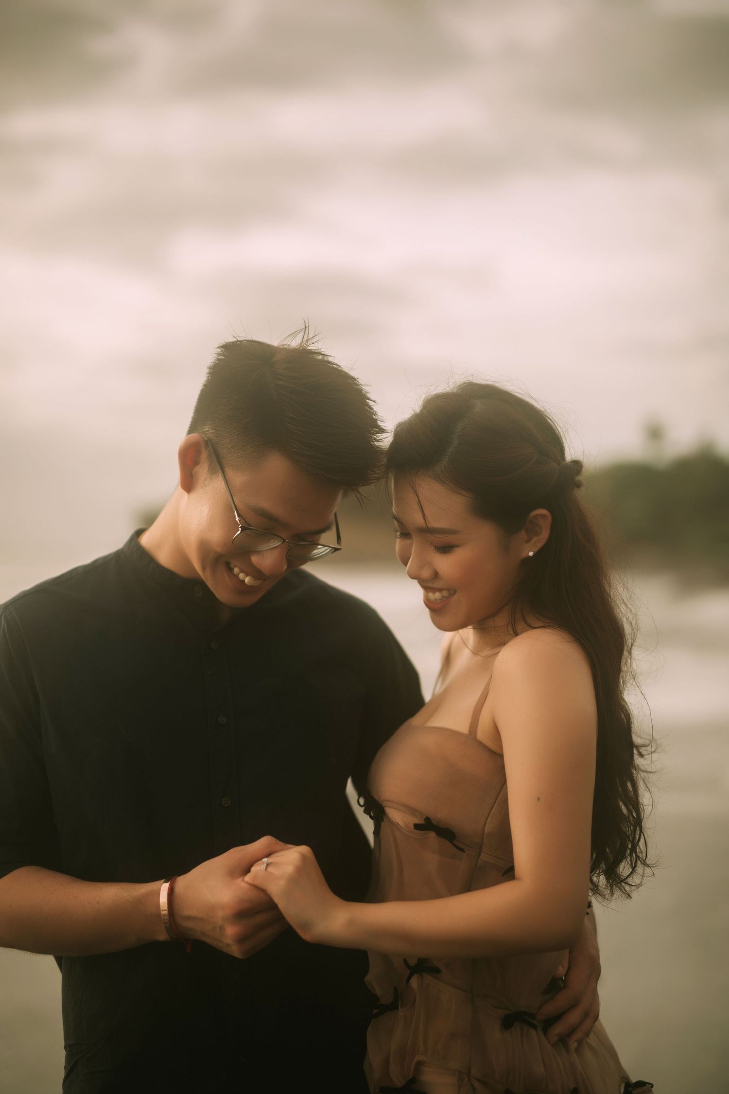 Couple shares joyful laughter during an intimate beach photoshoot.