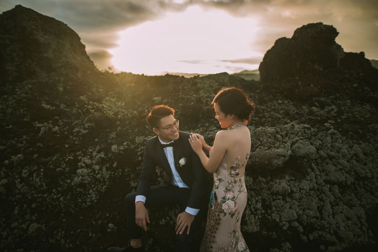Wedding couple shares intimate moment against rocky landscape at sunset.