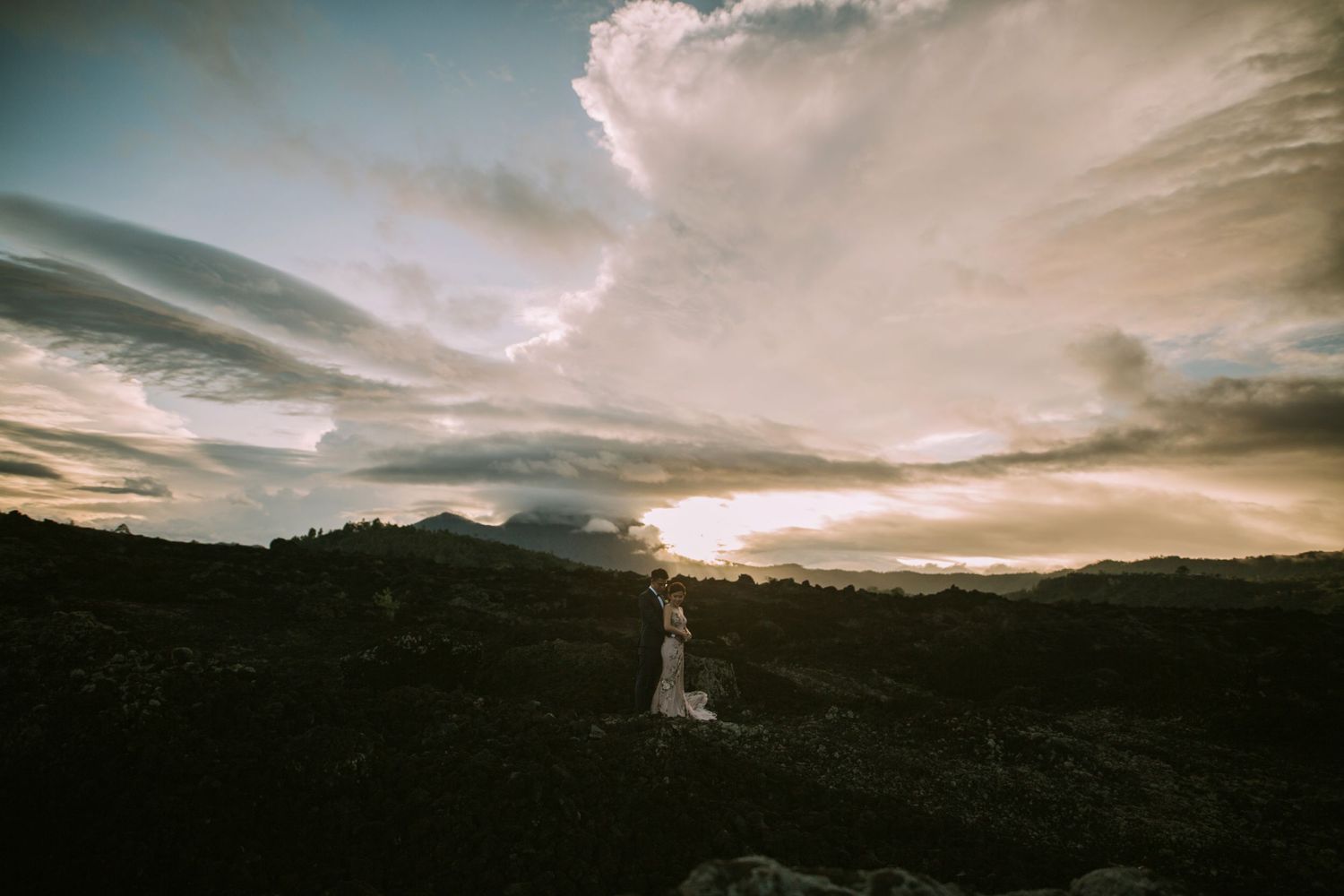 Dramatic sunset sky over mountainous landscape with moody clouds and golden light.