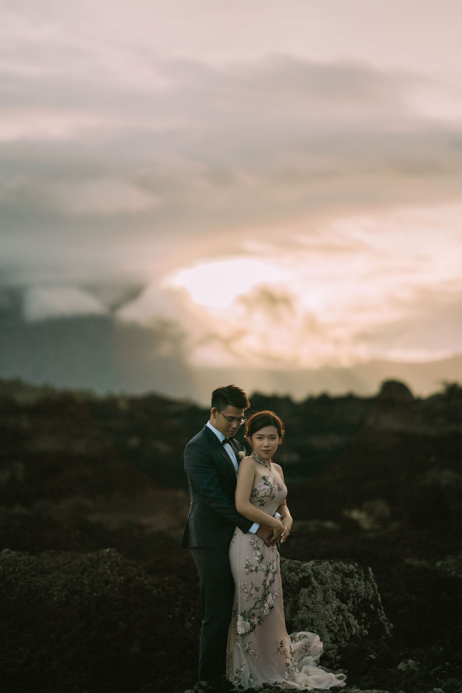 Romantic sunset portrait of couple on volcanic terrain with dramatic sky.