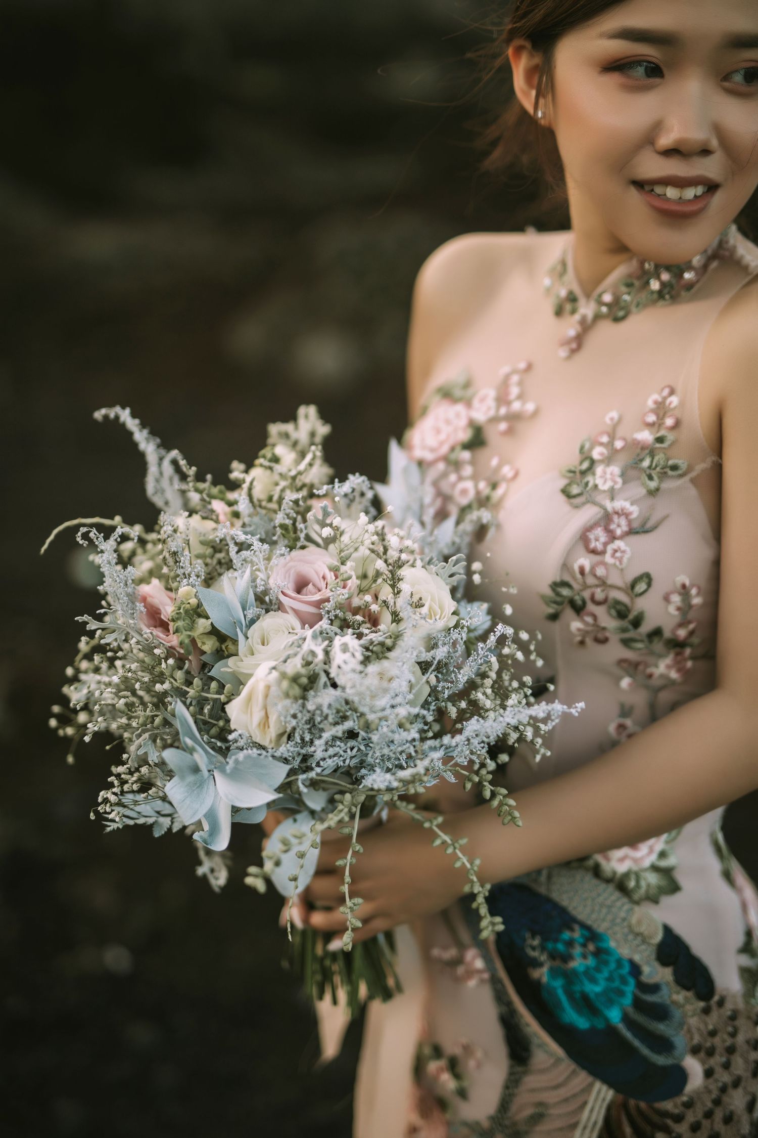 Delicate pastel bouquet with roses and baby's breath against floral dress.