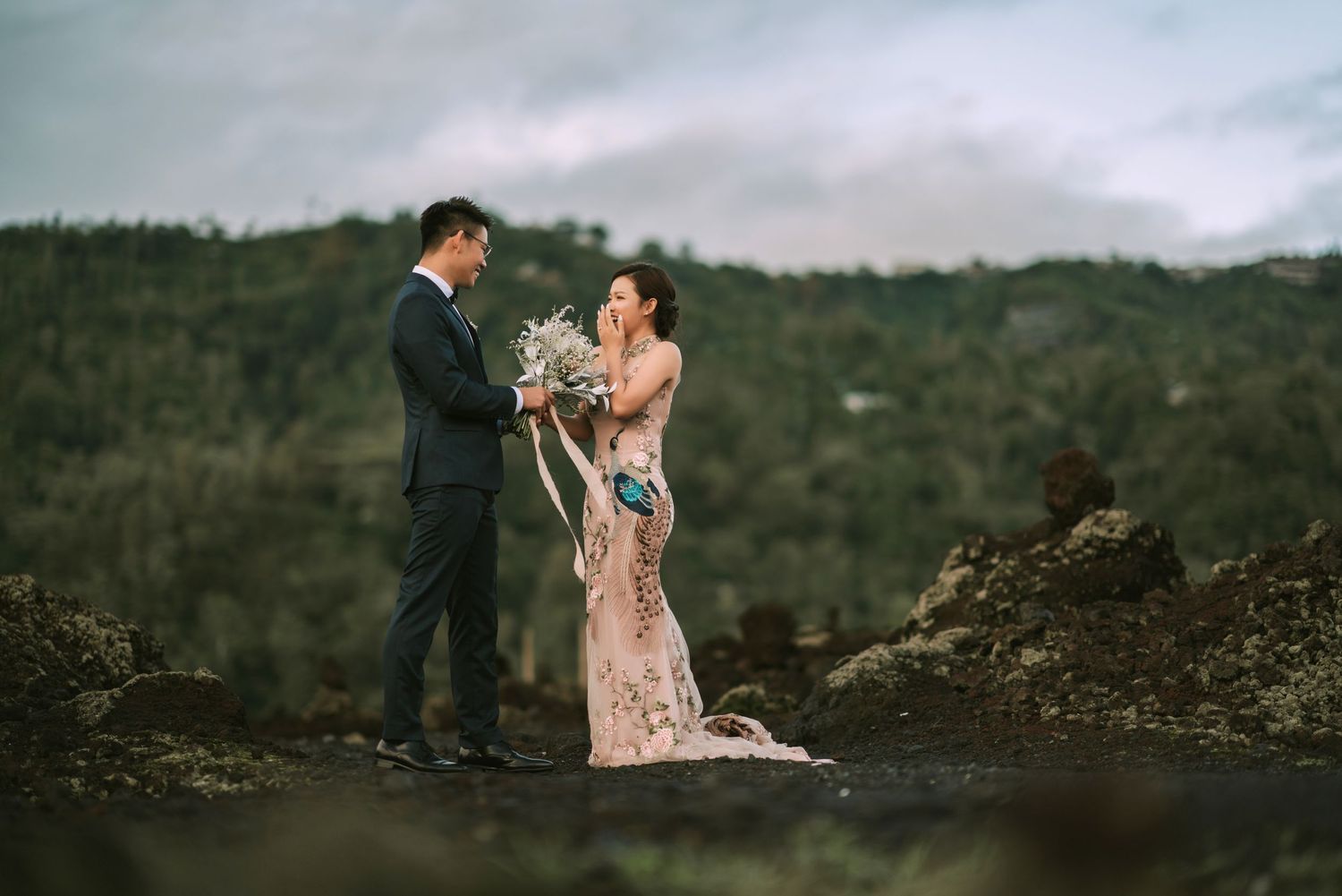 Couple shares romantic moment on rocky terrain with misty mountain views.