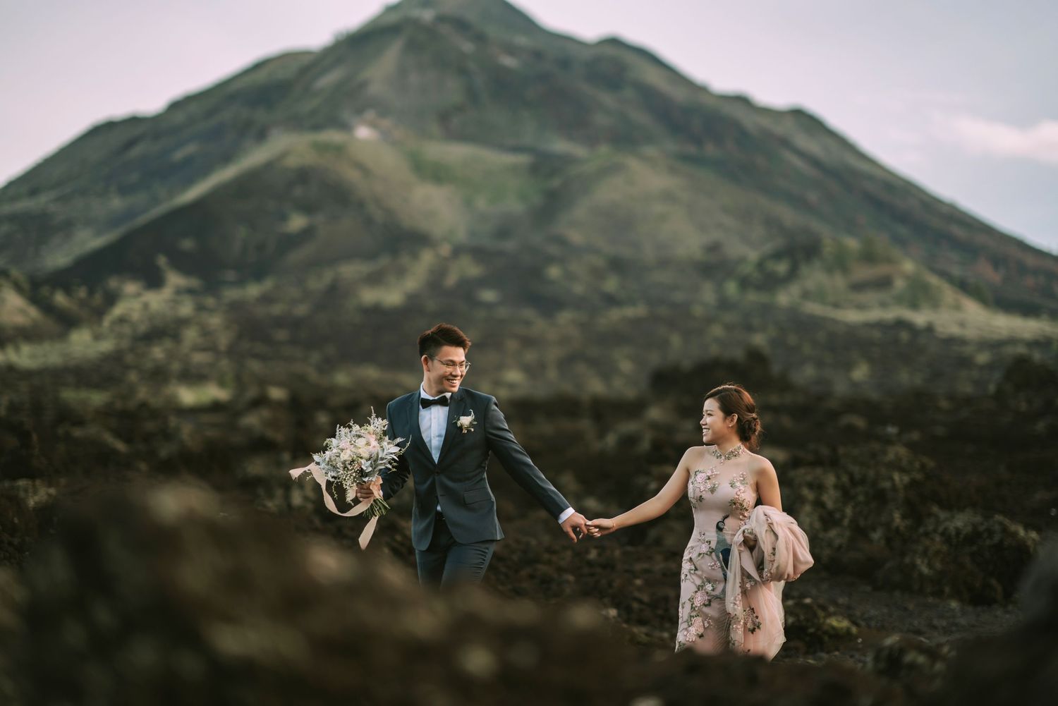 Wedding photo session on mountain ridge with dramatic cloudy sky backdrop.