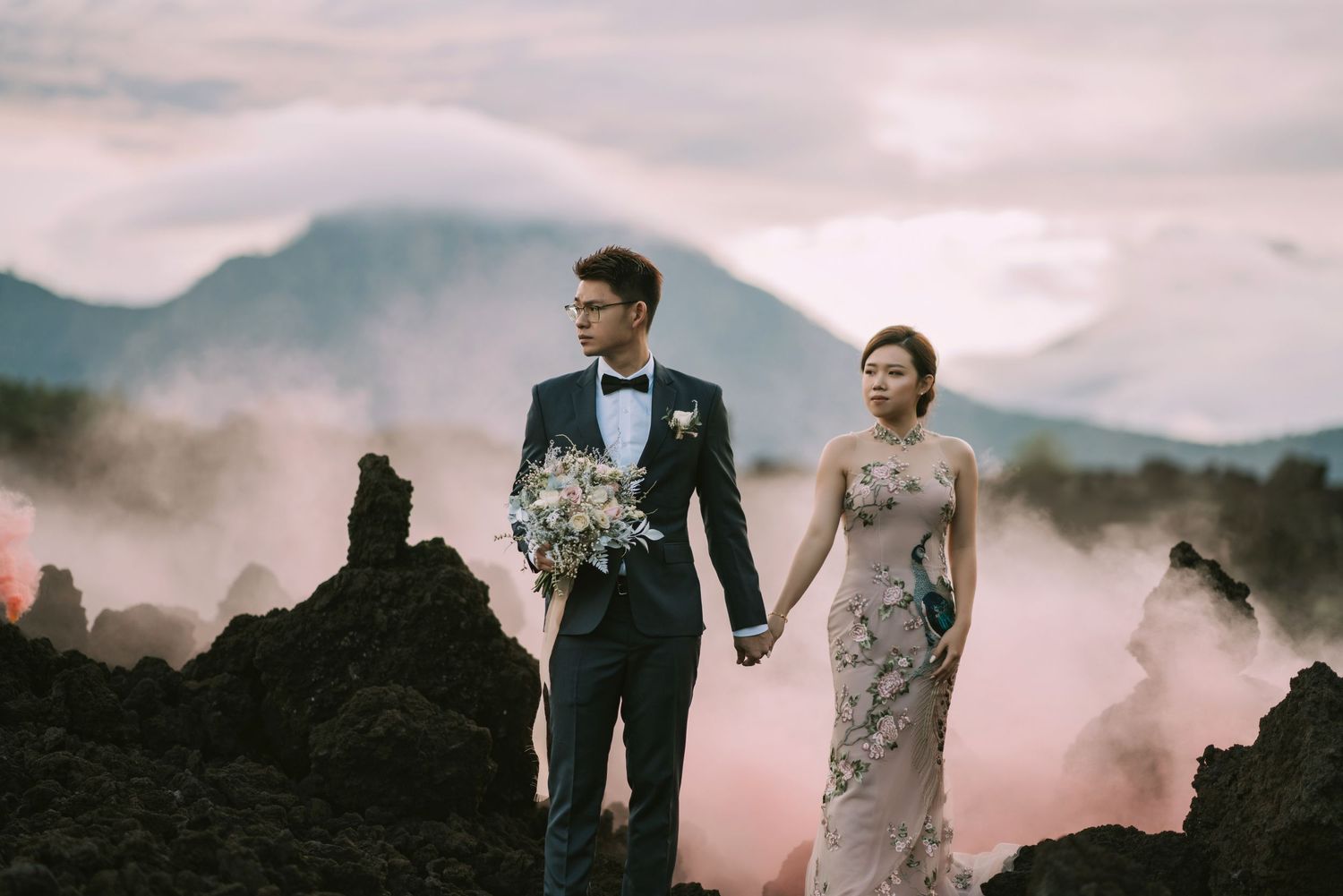 Romantic couple photoshoot against misty mountain landscape at sunset.