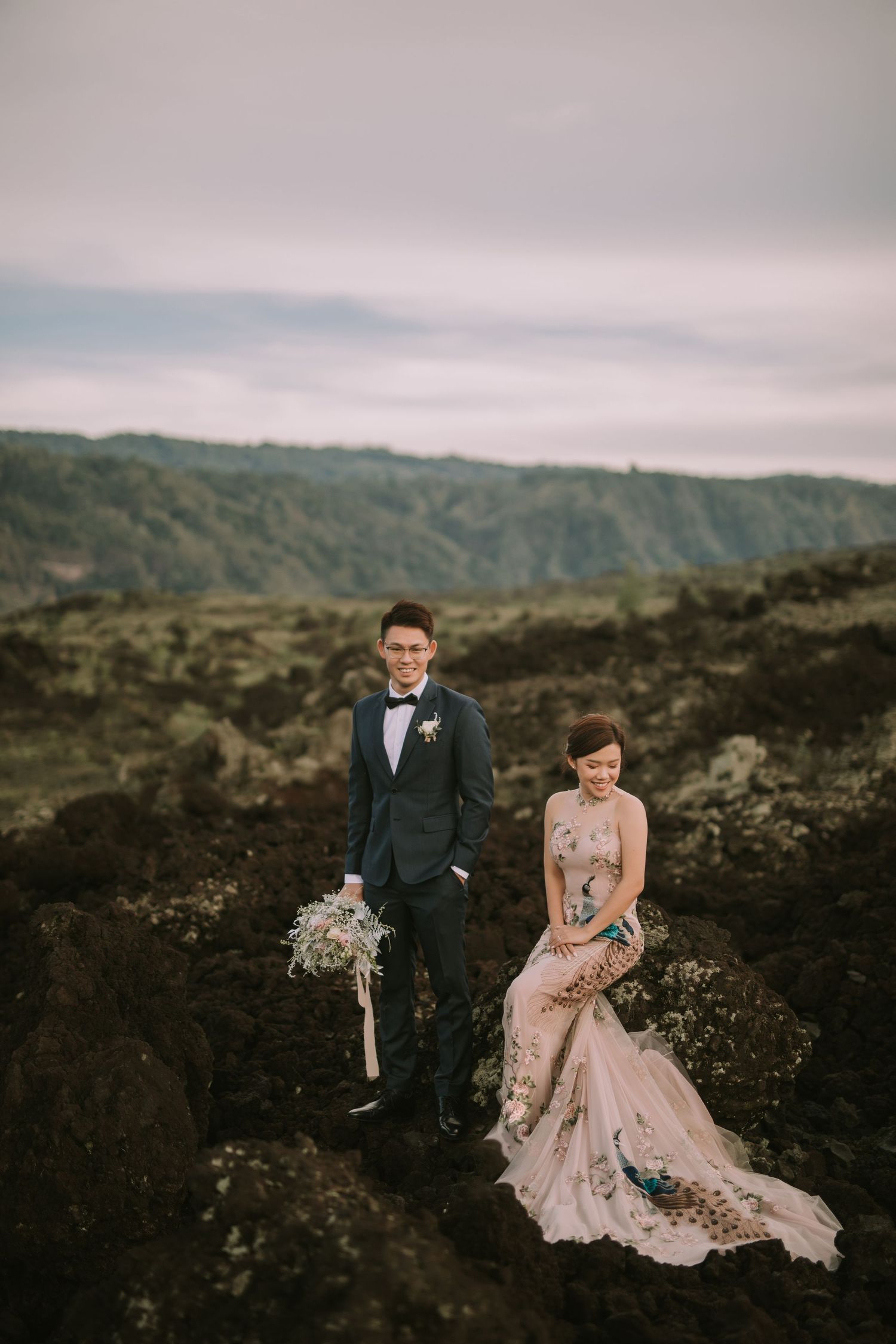 Newlyweds share an intimate moment on dramatic black lava rocks during their wedding photoshoot.