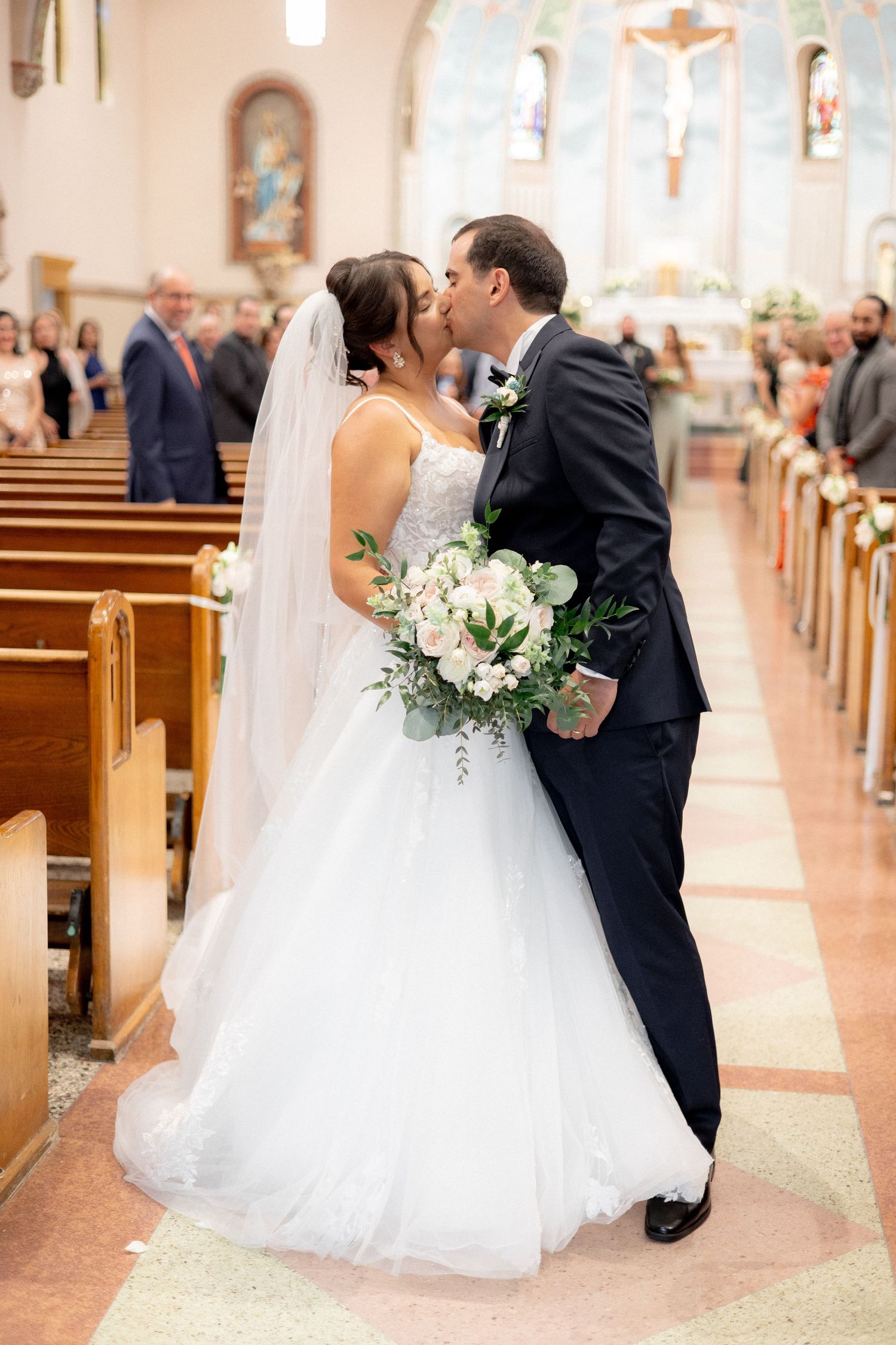 Romantic moment in church aisle with white bridal bouquet.