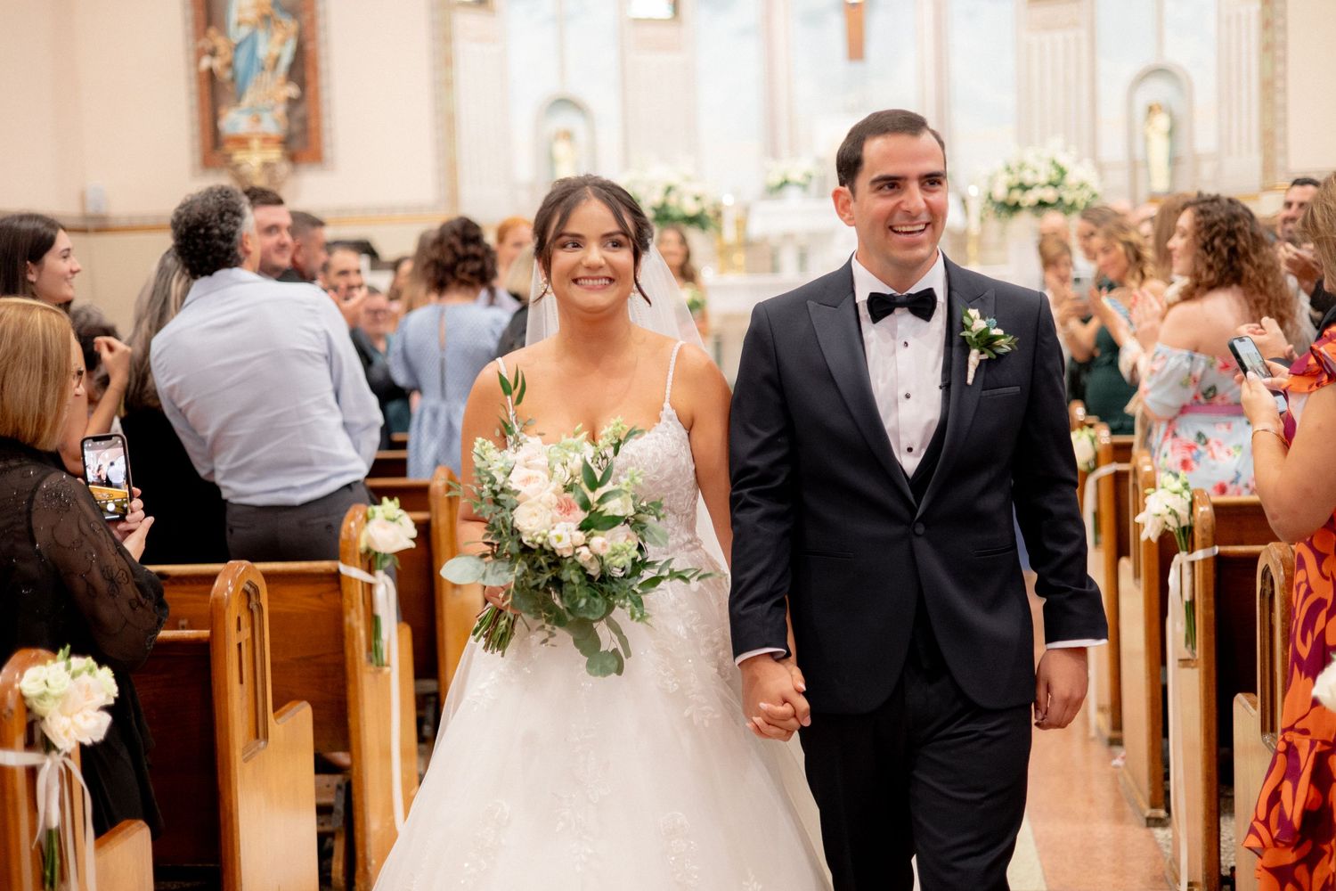 Joyful couple walking down the church aisle with wedding bouquet.